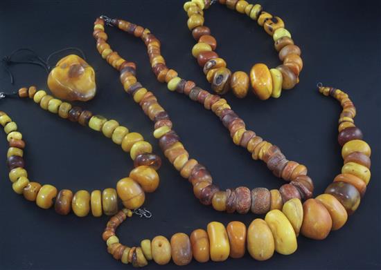 Four large amber bead necklaces of disc or pebble form and an amber pendant, longest necklace 33in.